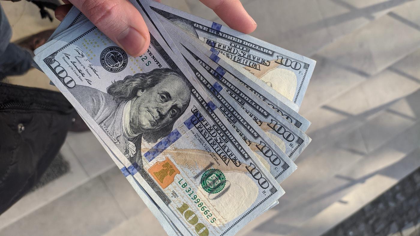 Hand holding $100 bills