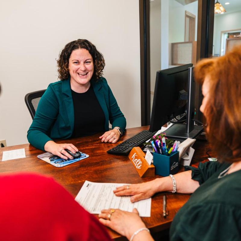 An Adirondack Regional FCU Banker with two members at an office desk